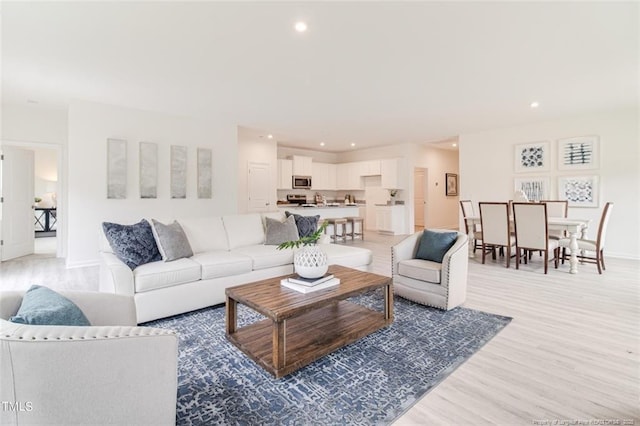 living area with recessed lighting, light wood-style flooring, and baseboards
