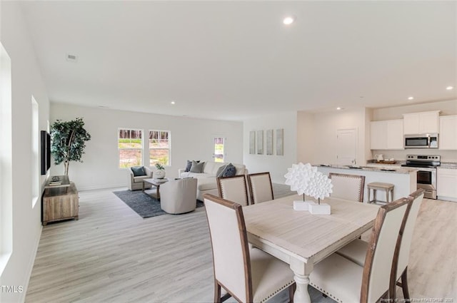 dining space with light wood-style flooring, recessed lighting, and baseboards