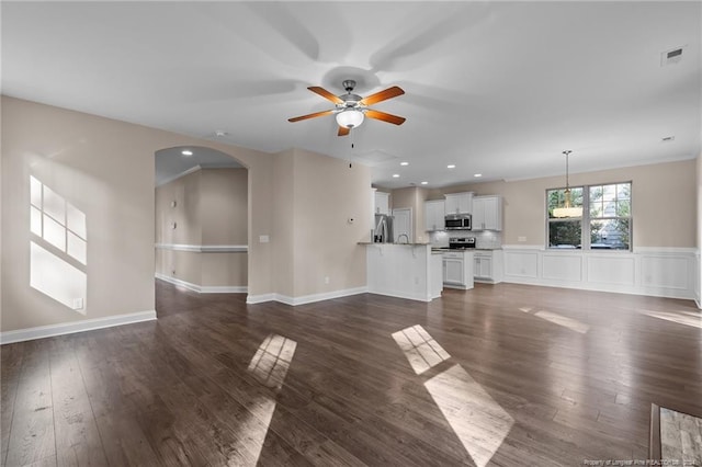 unfurnished living room with ceiling fan, dark hardwood / wood-style floors, and ornamental molding