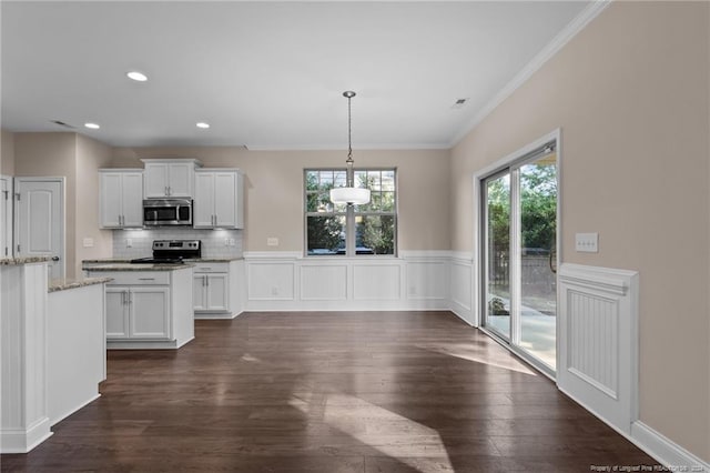 kitchen with light stone counters, dark hardwood / wood-style floors, stainless steel appliances, hanging light fixtures, and white cabinetry