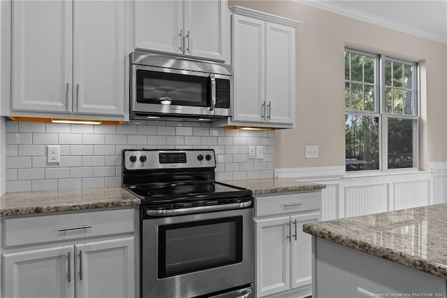 kitchen with light stone counters, tasteful backsplash, white cabinets, crown molding, and appliances with stainless steel finishes