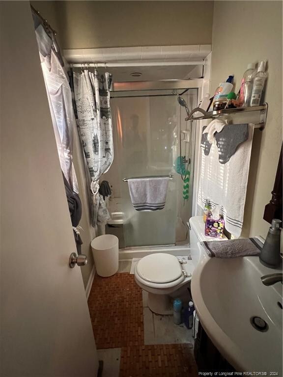 full bathroom with shower / bath combination with curtain, sink, toilet, and tile patterned floors