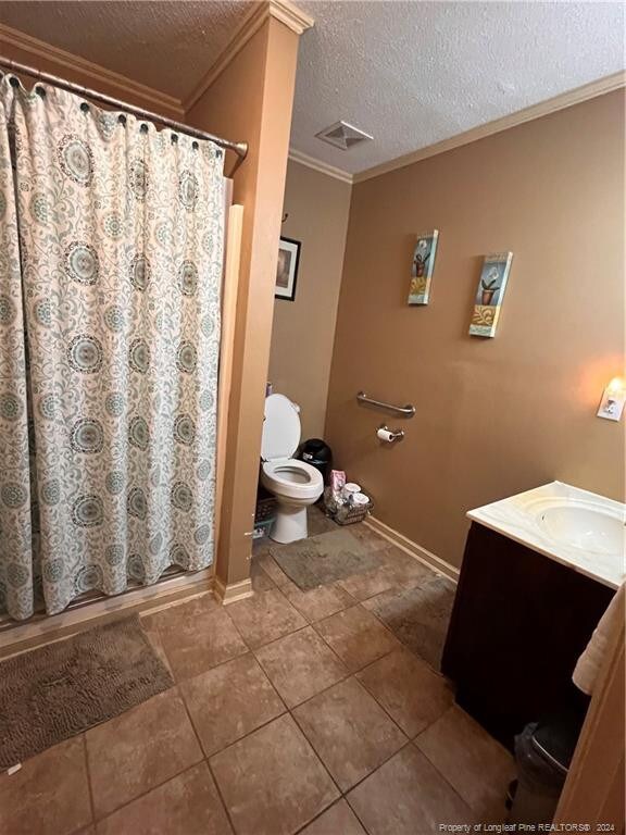 bathroom with crown molding, a shower with shower curtain, vanity, and toilet