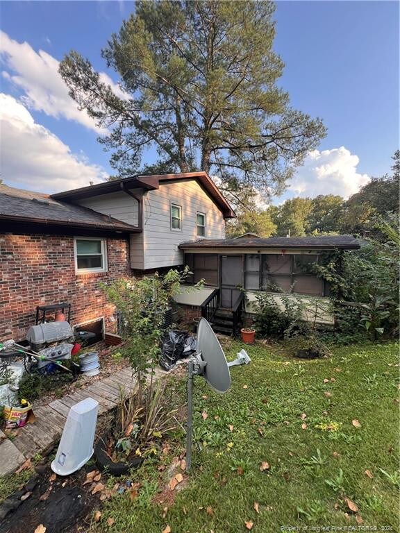 back of property with a sunroom and a yard