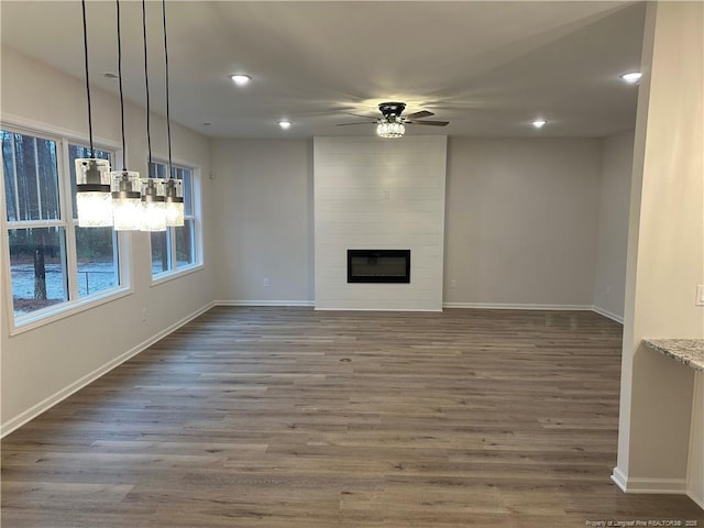 unfurnished living room featuring a fireplace, dark hardwood / wood-style floors, and ceiling fan