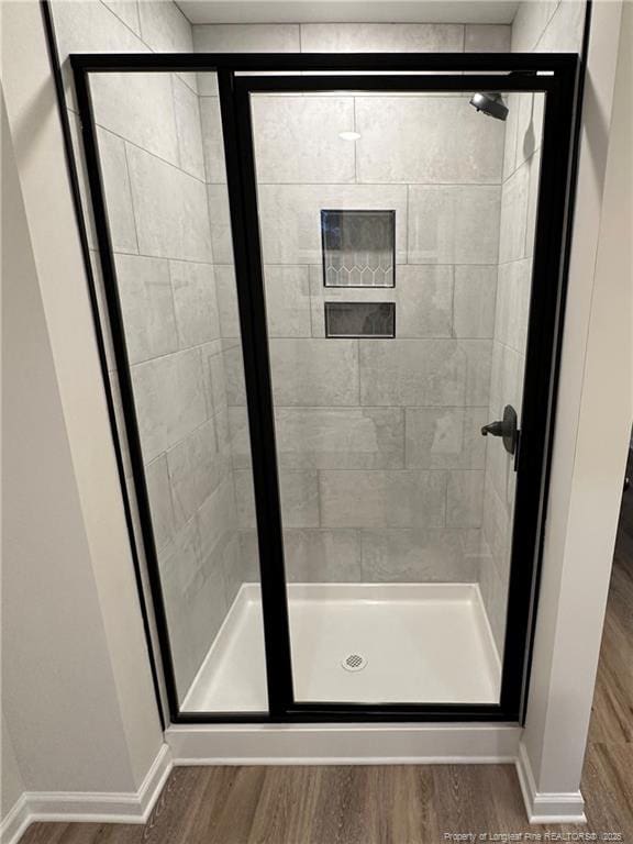 bathroom with hardwood / wood-style floors and a shower with shower door