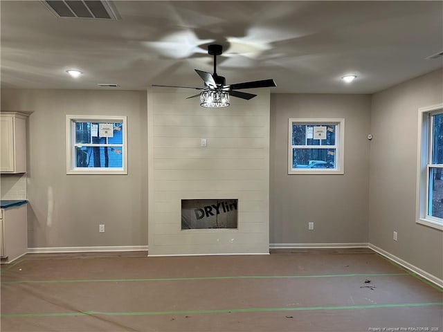 unfurnished living room with a large fireplace and ceiling fan