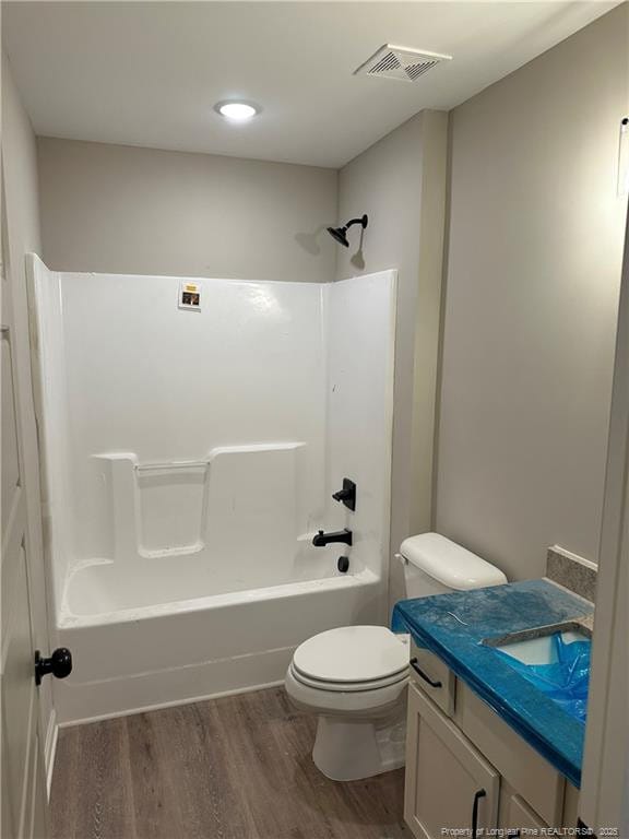 full bathroom featuring wood-type flooring, toilet,  shower combination, and vanity