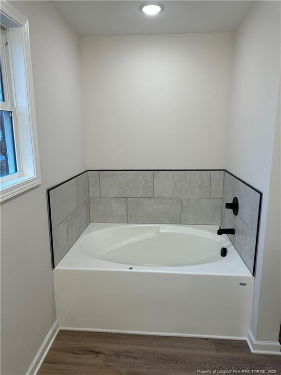 bathroom with hardwood / wood-style flooring and a tub