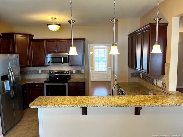 kitchen with a breakfast bar, decorative light fixtures, stainless steel appliances, and kitchen peninsula