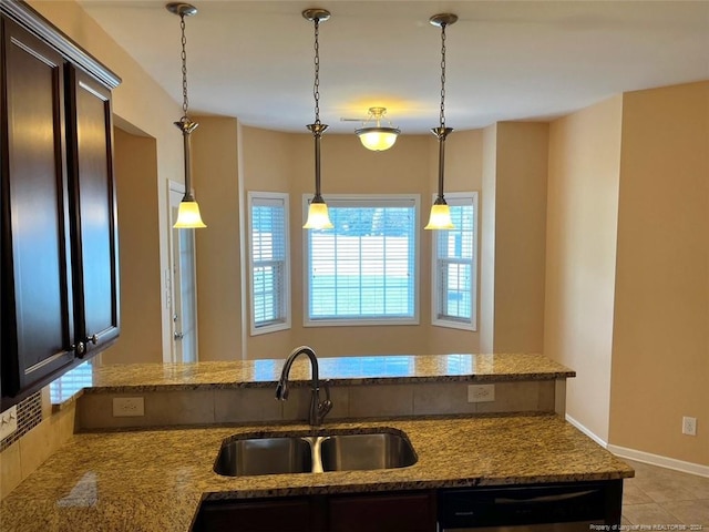 kitchen with light tile patterned floors, dark brown cabinets, sink, and decorative light fixtures