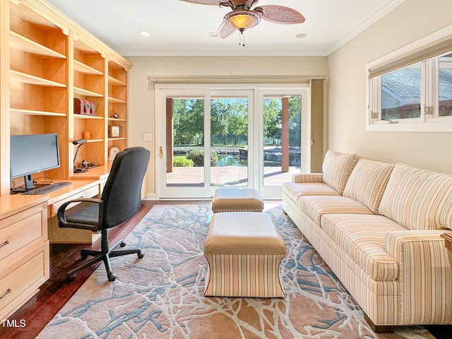 office space featuring built in desk, hardwood / wood-style floors, ceiling fan, a water view, and ornamental molding