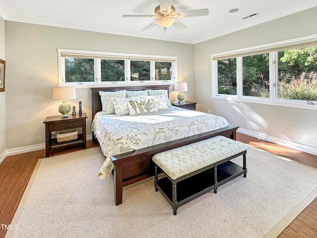 bedroom featuring multiple windows, ornamental molding, hardwood / wood-style flooring, and ceiling fan