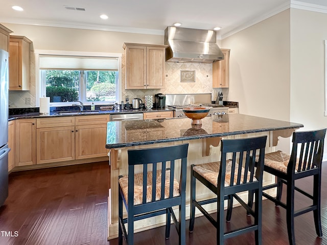 kitchen with dark hardwood / wood-style floors, dark stone countertops, sink, wall chimney exhaust hood, and a center island