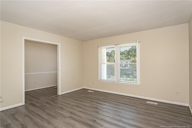 spare room featuring a textured ceiling and dark wood-type flooring