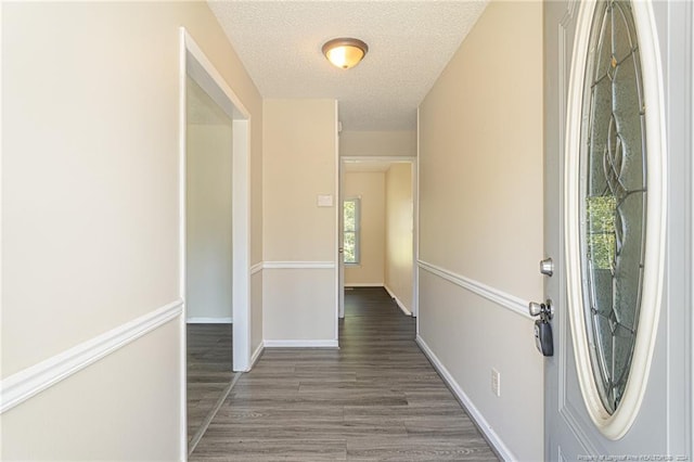 hall with a textured ceiling and dark hardwood / wood-style flooring