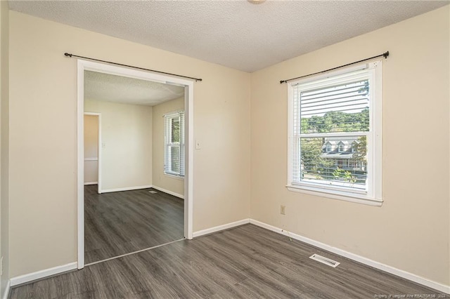 empty room with dark hardwood / wood-style flooring and a textured ceiling