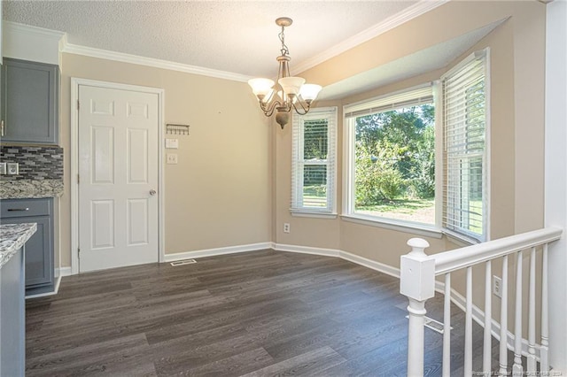 unfurnished dining area featuring a textured ceiling, dark hardwood / wood-style floors, and ornamental molding