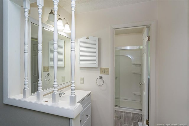 bathroom with a shower with door, hardwood / wood-style floors, vanity, and a textured ceiling