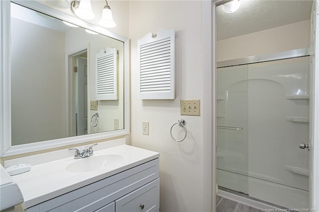 bathroom featuring a shower with door, hardwood / wood-style floors, vanity, and a textured ceiling