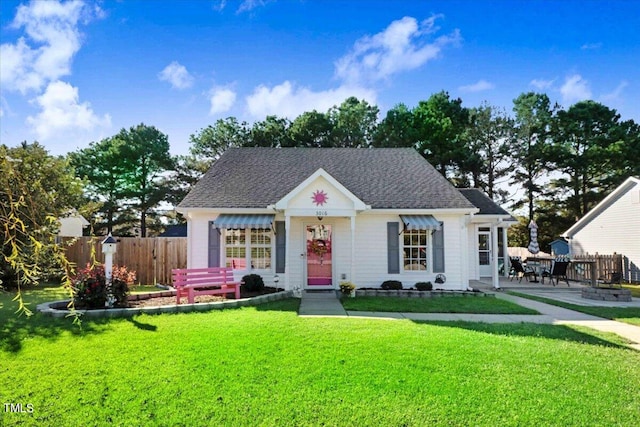 view of front of home with a patio area, roof with shingles, a front yard, and fence