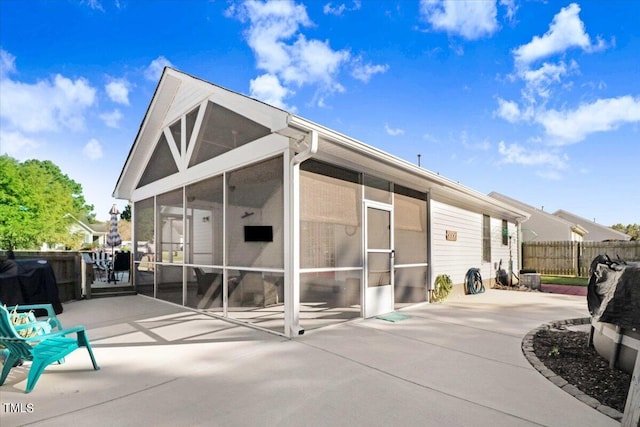 rear view of property featuring a patio area, fence, and a sunroom