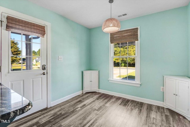 unfurnished dining area featuring baseboards, visible vents, and wood finished floors