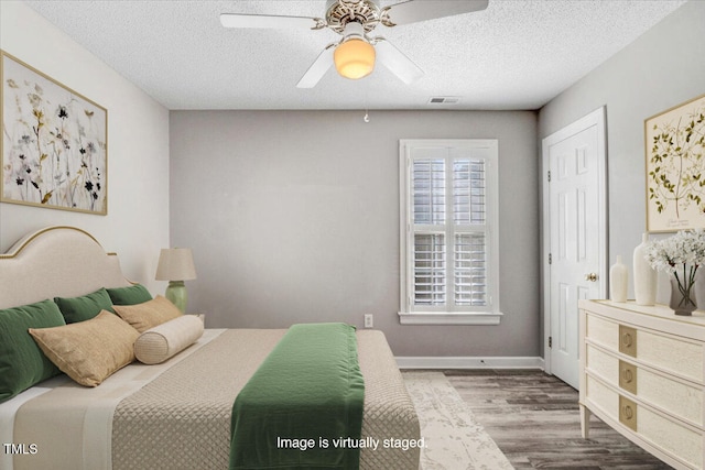 bedroom featuring hardwood / wood-style flooring, ceiling fan, and a textured ceiling