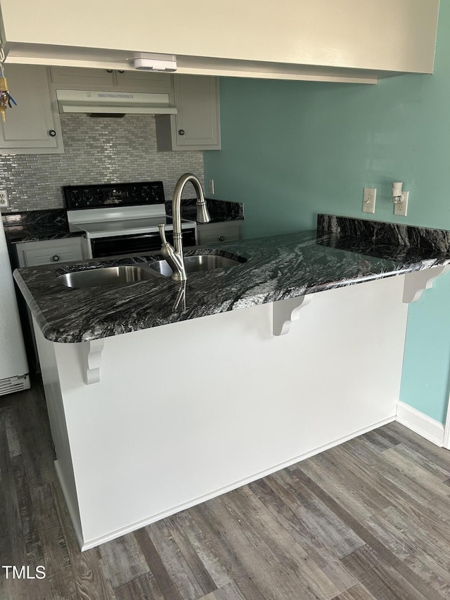 kitchen featuring gray cabinetry, electric range, dark hardwood / wood-style floors, a kitchen breakfast bar, and kitchen peninsula