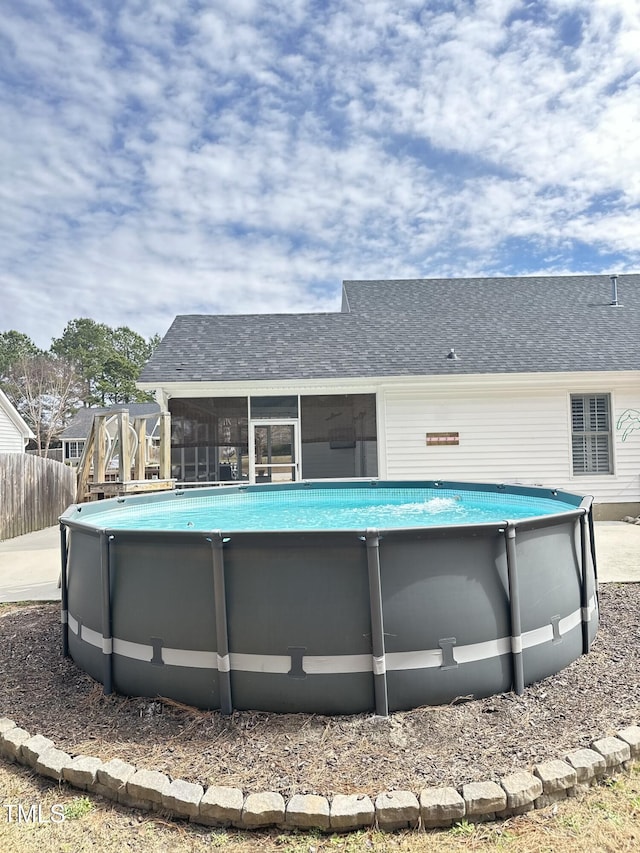 outdoor pool featuring a sunroom and fence