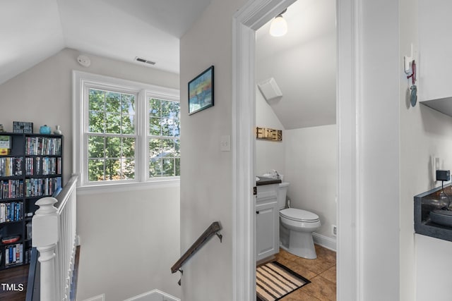 bathroom with vaulted ceiling, toilet, and tile patterned floors