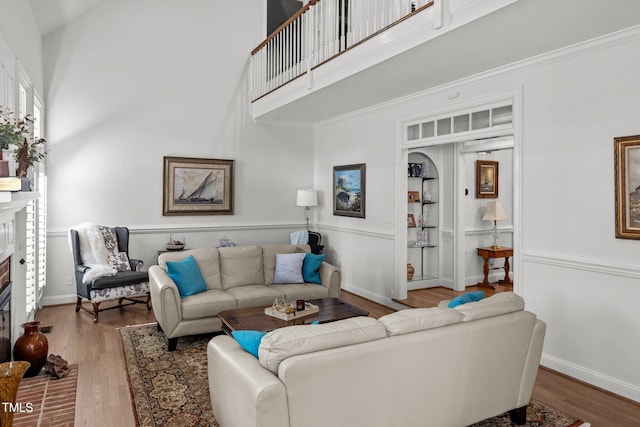 living room featuring a towering ceiling, a brick fireplace, and hardwood / wood-style floors