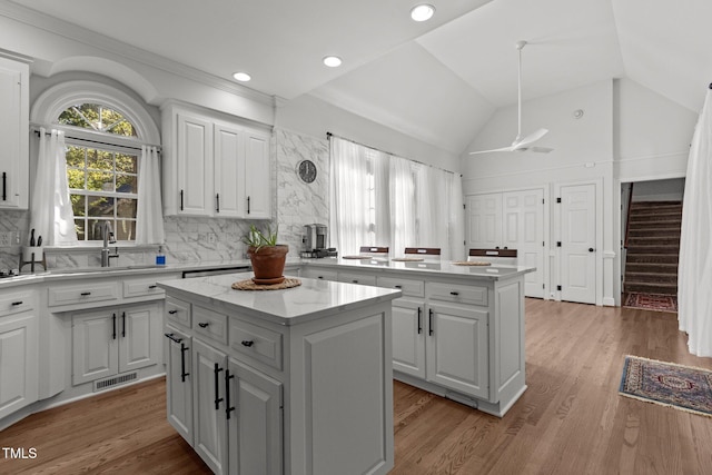 kitchen featuring light wood-type flooring, white cabinets, a center island, and ceiling fan