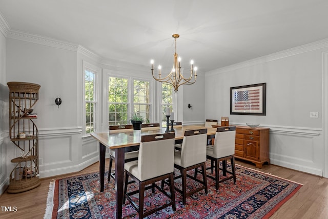 dining room with an inviting chandelier, light hardwood / wood-style flooring, and crown molding