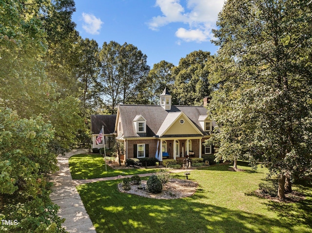 cape cod-style house featuring a front lawn and covered porch