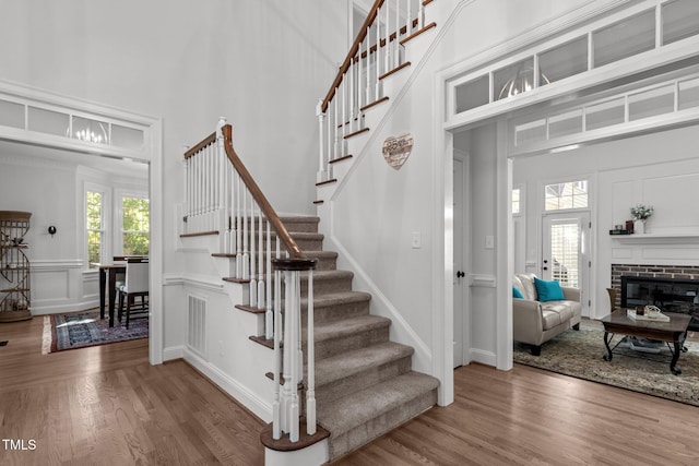 stairs featuring a fireplace, a high ceiling, and hardwood / wood-style floors