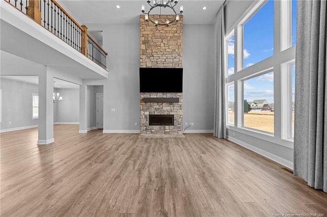 unfurnished living room with plenty of natural light, a fireplace, a chandelier, and light wood-type flooring