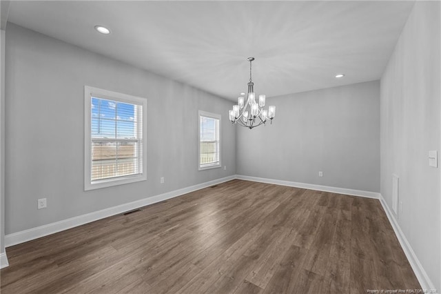 spare room with dark wood-type flooring and a notable chandelier