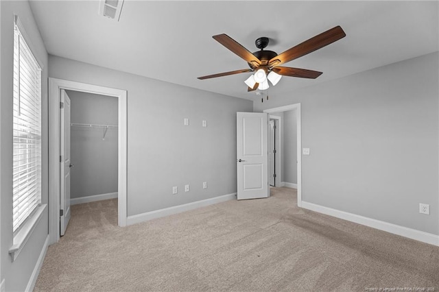 unfurnished bedroom featuring multiple windows, a spacious closet, light carpet, and a closet