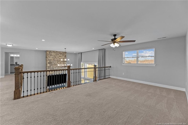 carpeted spare room with ceiling fan with notable chandelier