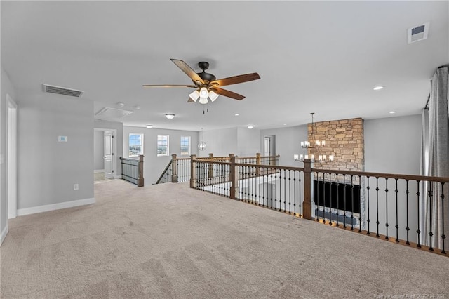 carpeted spare room featuring ceiling fan with notable chandelier