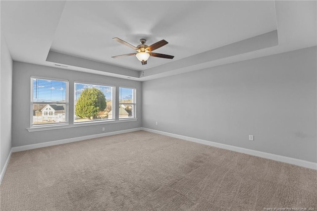 spare room featuring a tray ceiling, carpet floors, and ceiling fan