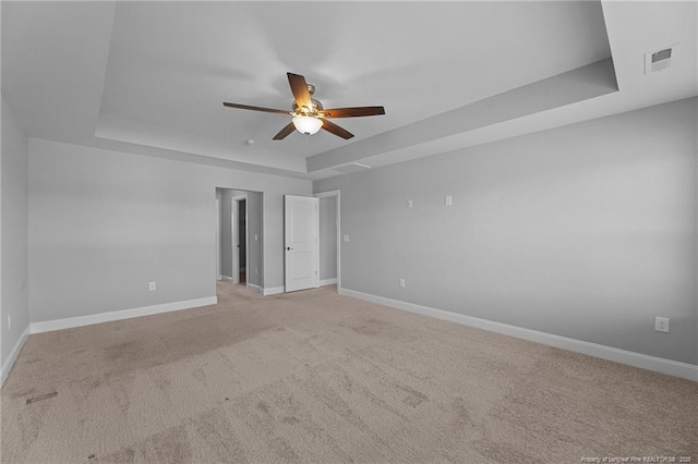 carpeted empty room with a tray ceiling and ceiling fan