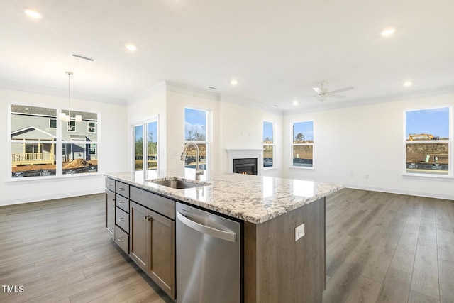 kitchen with dishwasher, a kitchen island with sink, light stone counters, sink, and decorative light fixtures