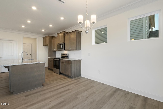 kitchen featuring stainless steel appliances, sink, light stone counters, a kitchen island with sink, and a notable chandelier