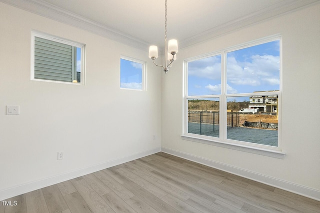 empty room with hardwood / wood-style flooring, crown molding, and a chandelier