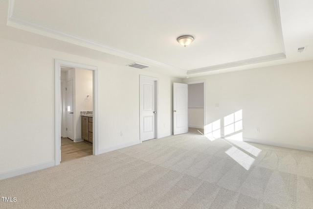 carpeted empty room featuring ornamental molding and a tray ceiling