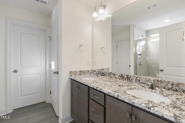 bathroom featuring vanity, an inviting chandelier, a shower with shower door, and hardwood / wood-style flooring