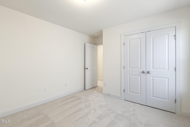 unfurnished bedroom featuring light colored carpet and a closet