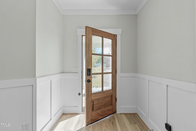 entryway with light wood finished floors, a decorative wall, and a wainscoted wall